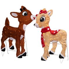 two stuffed deers are standing next to each other on a white background, one is wearing a red bow