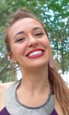 a woman smiling and holding a cell phone to her ear