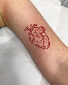 a small heart tattoo on the arm