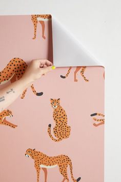 a person's hand on top of a pink surface with cheetah wallpaper