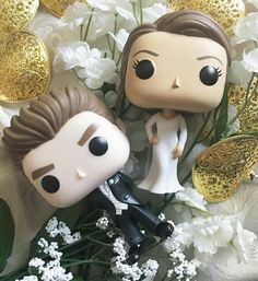 two bride and groom figurines sitting next to each other on top of flowers