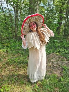 a woman dressed in an old fashioned costume and holding a large hat over her head