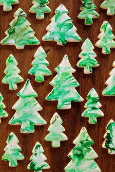 green and white christmas tree cookies on a wooden table with icing in the shape of trees