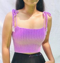 a woman wearing a purple crop top and black shorts with her hands in her pockets