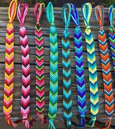 several colorful braided bracelets hanging on a wooden fence