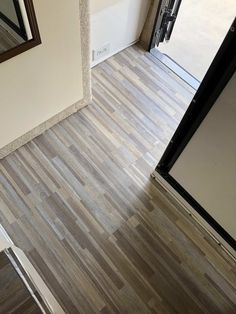 an overhead view of a wooden floor in a room with a door and mirror on the wall