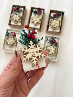 a hand holding a snowflake ornament in front of four other ornaments