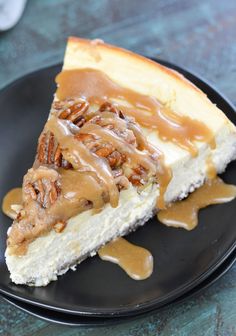 a slice of pecan cheesecake on a black plate with caramel drizzle