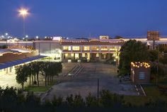 an empty parking lot at night in front of a large building with lights on it