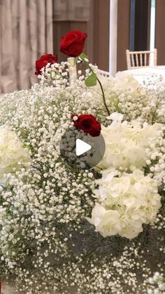 a vase filled with white and red flowers on top of a table next to candles