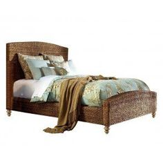 a wicker bed with pillows and blankets on it