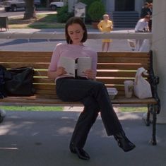 a woman sitting on a bench reading a book