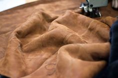 the sewing machine is next to an unmade brown cloth with stitching on it