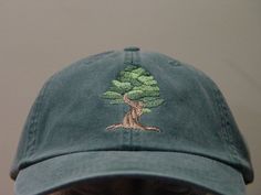 a man wearing a green hat with a tree embroidered on the front and side of it