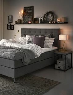 a bedroom with a bed, nightstands and pictures on the wall above it in grey tones