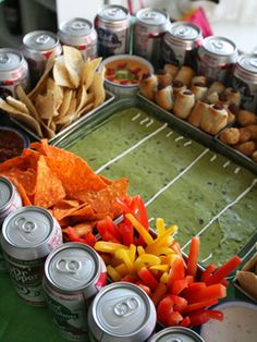 an assortment of food and drinks on a football field platter with dips, chips, and hotdogs