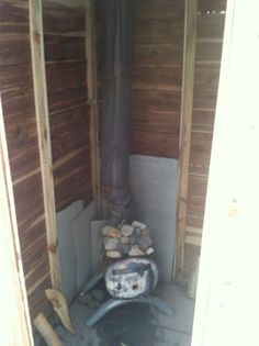 the inside of a building with wood stacked on top of it and a pipe in the corner