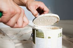 a person using a brush to paint a can