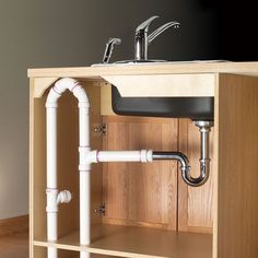 an open cabinet with pipes running from the top to the bottom, and a sink below