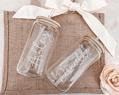 two personalized mason jars are sitting on a burlock with a white ribbon