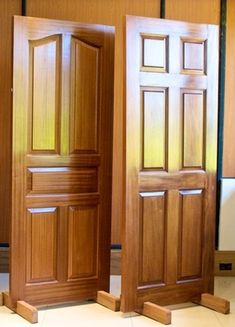 two wooden doors sitting next to each other on top of a tile floor in front of wood paneled walls