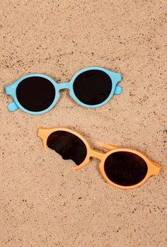 two pairs of sunglasses laying on the sand