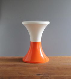 an orange and white vase sitting on top of a wooden table