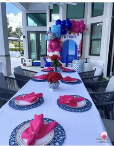 the table is set with plates, napkins, and pink and blue flowers on it