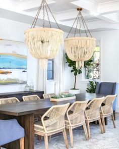 a dining room table with chairs and chandeliers hanging from the ceiling above it