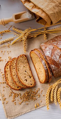 sliced loafs of bread sitting on top of a table next to some ears of wheat