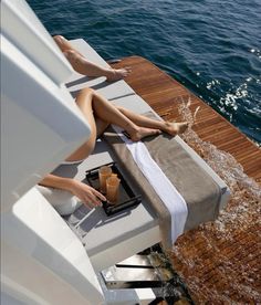 a woman laying on top of a boat next to a drink and tray with orange juice