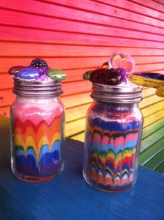 two jars filled with candy sitting on top of a blue table next to a rainbow colored wall