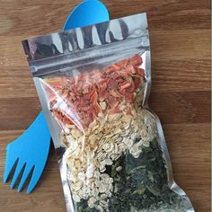 a bag of food sitting on top of a wooden table next to a blue fork