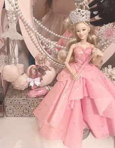 a barbie doll wearing a pink dress and tiara in front of a large mirror