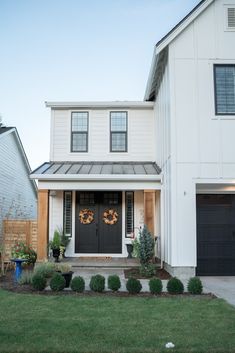 a white house with two black doors and green grass