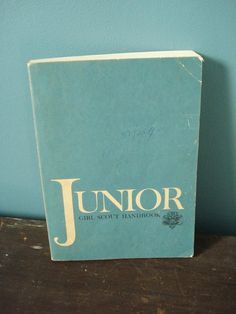 a book sitting on top of a wooden table next to a blue wall with the word junior written in gold