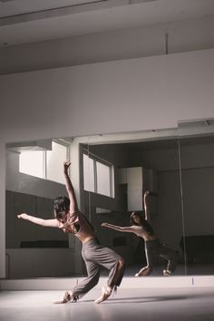 three people are doing tricks in an empty room with mirrors on the wall and floor