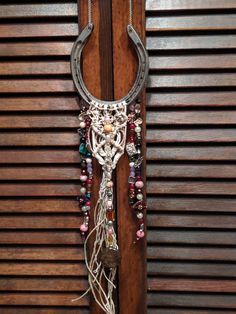 a cowgirl's necklace hanging on the side of a wooden door with a metal hook