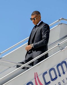 a man in a suit and sunglasses standing on top of a plane