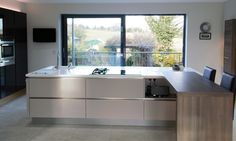 a modern kitchen with an island countertop and stainless steel appliances in front of a large window