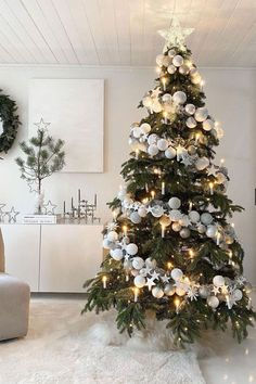 a decorated christmas tree in the corner of a living room with white and silver decorations