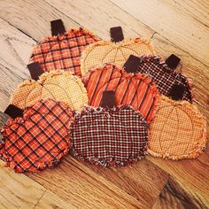 four pieces of fabric sitting on top of a wooden floor next to an orange and black pumpkin