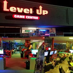 the level up game center is lit up with neon signs and people playing video games