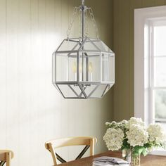 a chandelier hanging from the ceiling over a dining room table with flowers on it