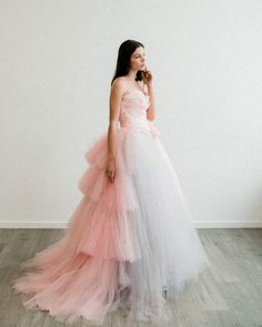 a woman wearing a pink and white dress standing in front of a wall with her hand on her face