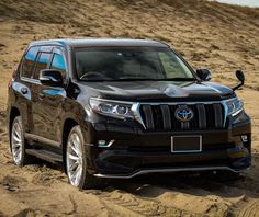 a black suv is driving through the sand