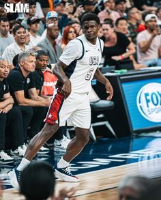 a basketball player dribbling the ball during a game with fans in the stands