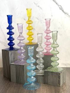 there are many different colored glass vases on the table