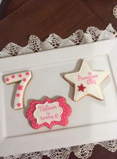 two decorated cookies in the shape of stars on a white tray with lace doily