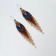 two pairs of beaded earrings on a white surface, one with blue and red beads